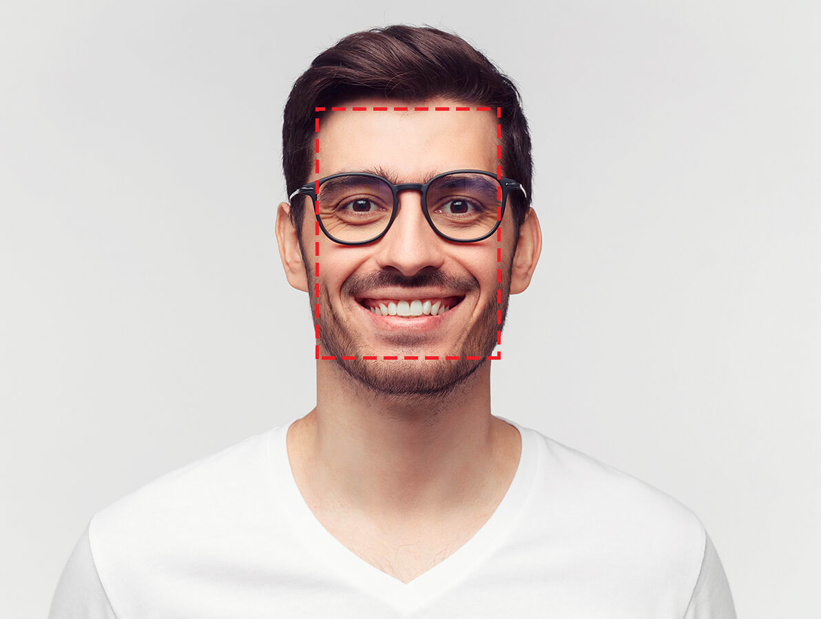 Mann med svarte briller ser inn i kameraen og smiler. Røde streker er tegnet i en firkant rundt mannens ansikt.