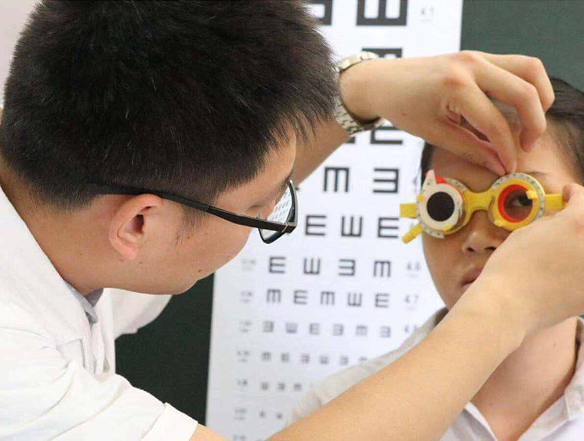 Vuxen man justerar en optisk linsram på ett barn