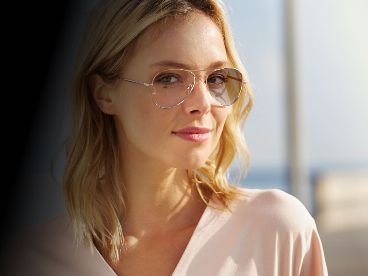 Blond kvinne med solbriller med fotokromatiske solglass.