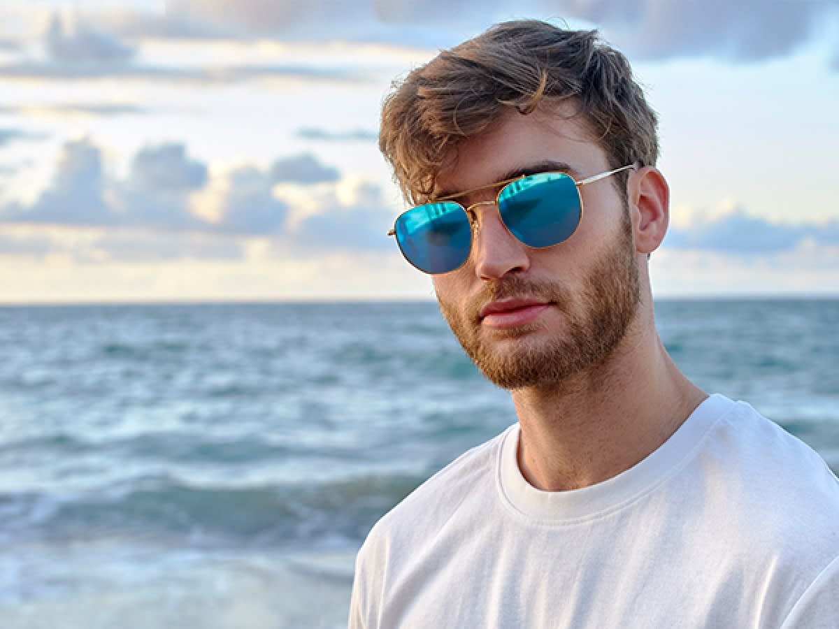 Mann med solbriller med speilglass foran havet.
