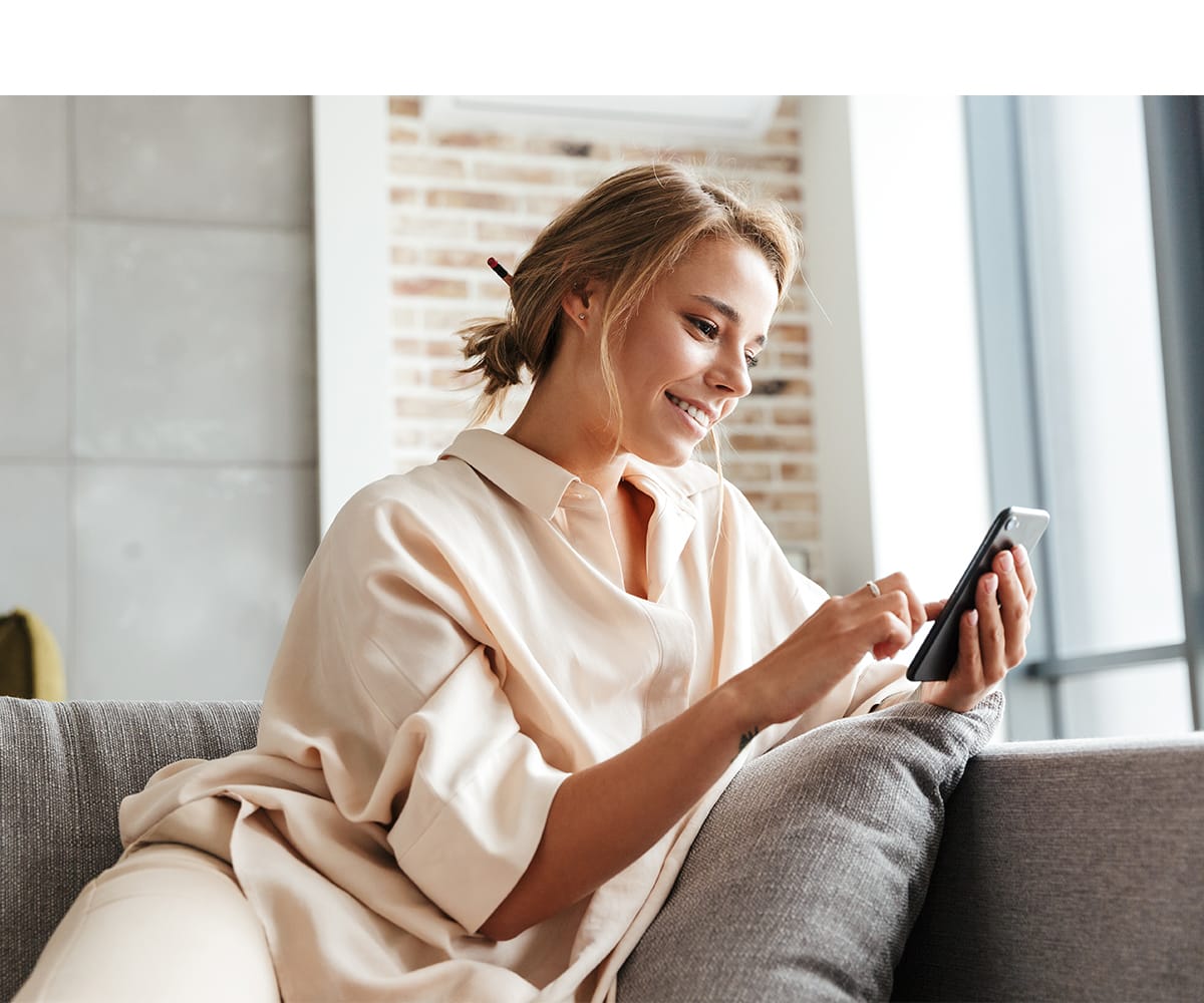 Tjej som sitter i soffan och scrollar på telefonen.