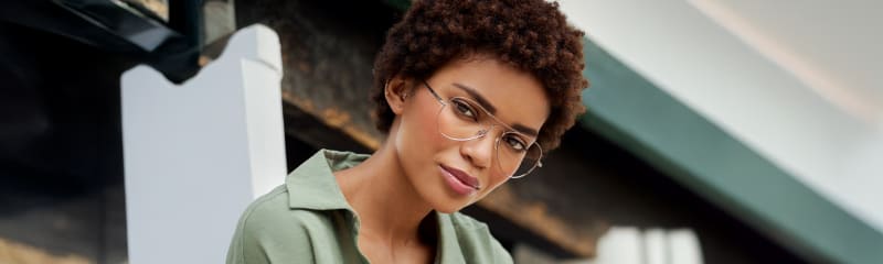 A woman wearing C. Jacobsen aviator eyeglasses, gazing confidently into the distance. The sleek, minimalist frame enhances her effortless Scandinavian style, complemented by soft natural lighting and a serene outdoor setting.