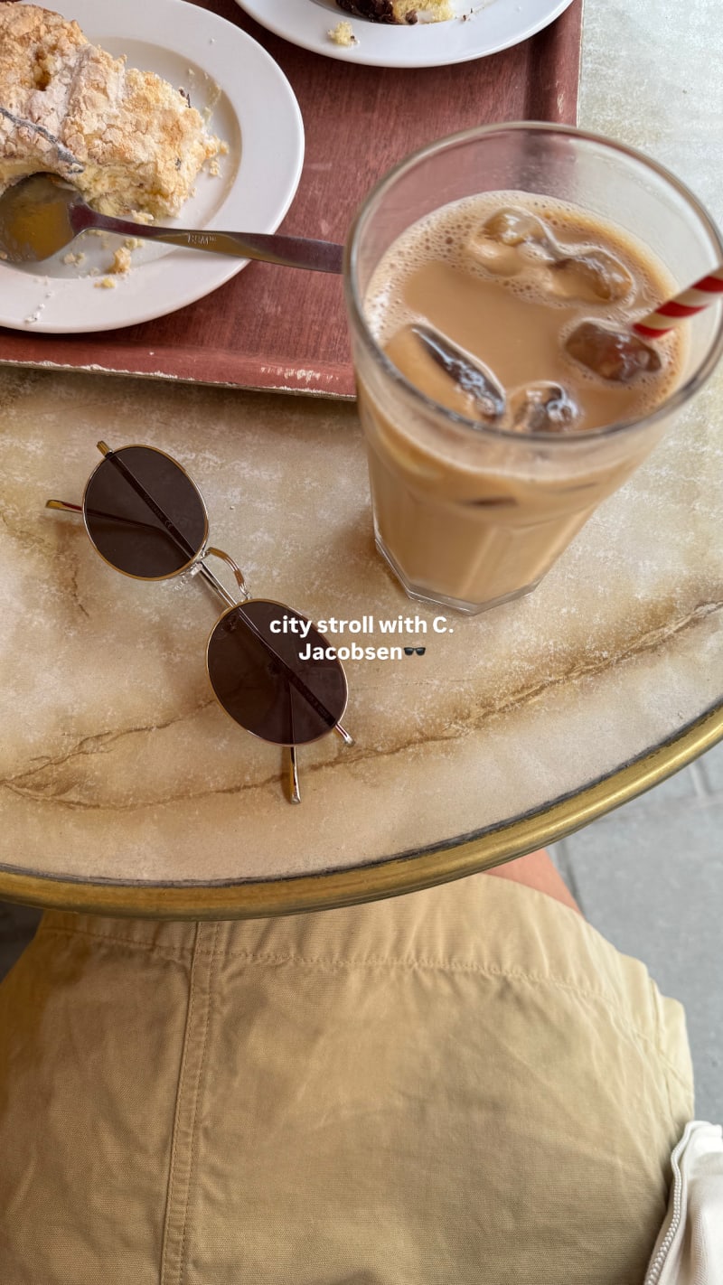 A photo of Dagg CJ2428 sunglasses, an iced latte, and a pastry on a marble table.
